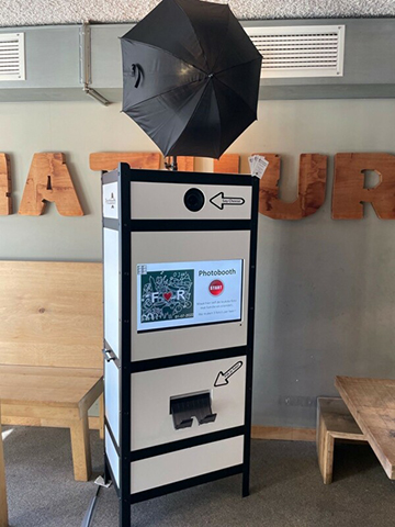 Photobooth met flitser en scherm in horecalocatie.